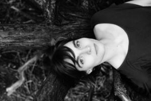 black and white head and shoulders photo of composer hildur guðnadóttir lying on a tree